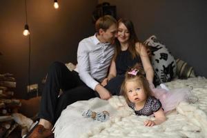 padre mamá y su pequeña hija de un año se divierten juntos antes de navidad. foto