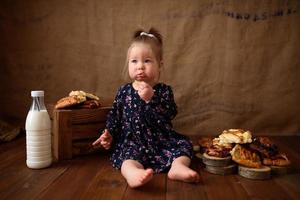 Little girl in the kitchen eats sweet pastries. photo