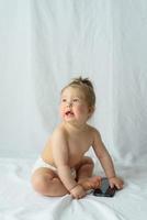 Cute little baby is talking on cell phone, isolated over white photo