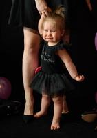 día de la fiesta de cumpleaños de la niña del primer año. globos y vacaciones en interiores. cumpleaños del niño niña bonita en su primer vestido negro foto