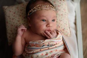 Newborn girl lying on a miniature crib photo