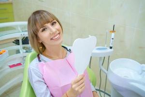 joven mujer feliz sentada en el consultorio del dentista, dientes sanos foto