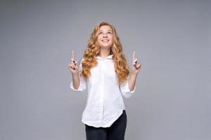 Photo positive girl with blond hair in white shirt shows thumb up an empty