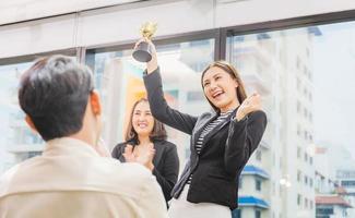 mujer de negocios con trofeo de premio en la sala de reuniones, concepto de equipo de felicidad de éxito de celebración foto