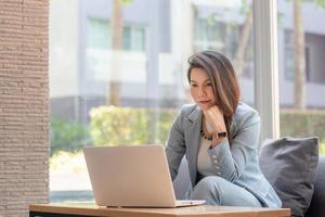 Beautiful Asian business woman working with computer laptop and thinking to get ideas, Business Startup Concept photo