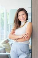 feliz, exitosa, inteligente, joven mujer de negocios asiática, de pie, relajada y sonriente en el cargo.