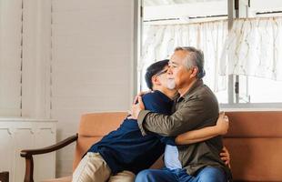 padre asiático mayor da consejos a un hijo adulto en la sala de estar, conceptos familiares de felicidad foto