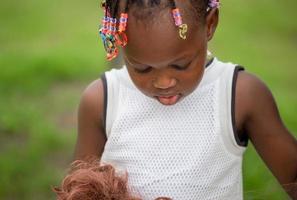 Cerca de una niña con muñeca en el parque con fondo verde borroso foto