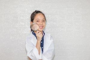 Dream careers concept, Portrait of Happy kid in science coat with magnifying glass on blurred background photo