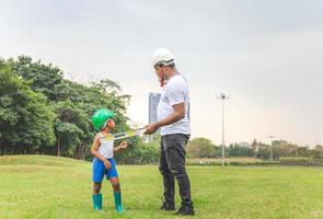 Cheerful african american father and son in hard hat in the park, Happiness family concepts photo