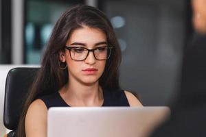 joven mujer de negocios en anteojos con computadora portátil en la sala de reuniones