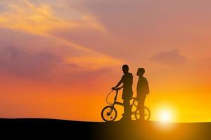 Silhouettes of mother and son playing at sunset evening sky background. photo