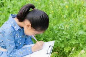 Little cute girl checking vegetable and writing record document in a farm, Learning outside the classroom concepts. photo