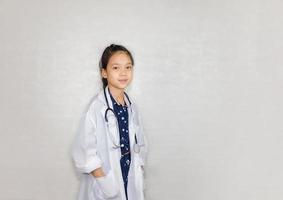 concepto de carrera de ensueño, retrato de un niño feliz con abrigo médico con estetoscopio en un fondo borroso foto