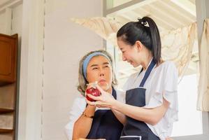 Senior asian mother and middle aged daughter cooking together at kitchen photo