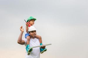 Cheerful african american father and son in hard hat, Happy dad carrying son on shoulders photo