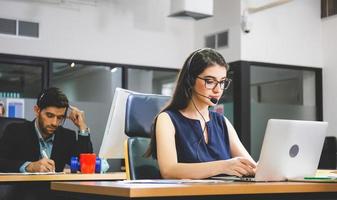 joven operadora telefónica con auriculares trabajando en una computadora portátil, ejecutiva de servicio al cliente trabajando en la oficina foto