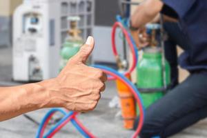 Technician man hand with clipping path giving thumb up, Over blurred repairman on the floor fixing air conditioning system background photo