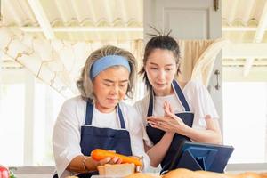 madre asiática mayor e hija de mediana edad cocinando juntas en la cocina foto