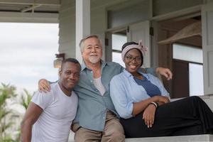 Senior asian man sitting relax with young cheerful african american man and woman and looking at camera photo