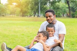 Cheerful african american father and two sons playing in park, Happiness family concepts, parent and childs play in park photo