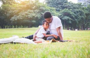 padre afroamericano e hijo haciendo un picnic en el parque, conceptos familiares de felicidad foto