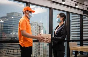 Woman wear face mask receiving parcel from delivery service, Young delivery man employee in t-shirt uniform wear face mask photo