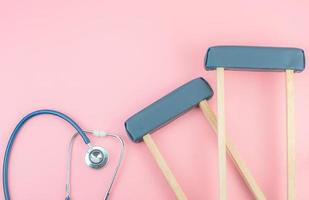 Top view with copy space of Crutchs and stethoscope on the pink pastel background, Flat lay and Healthy concept photo