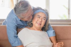 Close up portrait of happy senior asian couple hugging in living room photo