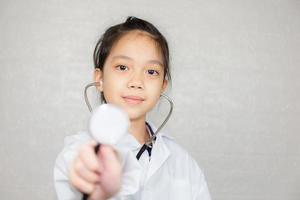 concepto de carrera de ensueño, retrato de un niño feliz con abrigo médico con estetoscopio en un fondo borroso foto