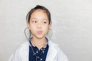 Portrait of Happy kid playing dream careers, Cheerful child in doctor coat with stethoscope blurred background photo