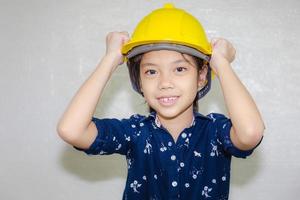 Dream careers concept, Portrait of Happy engineer kid in hard hat looking at camera on blurred background photo