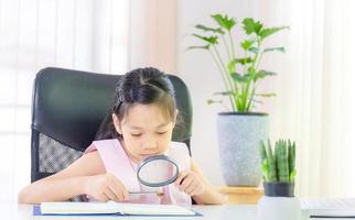 Cheerful little smiling girl learning with a magnifying glass, Education and distant concept photo