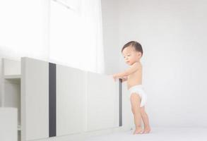 Portrait of happy little baby boy in diaper standing on the bed, Kids playing and Happiness concept photo