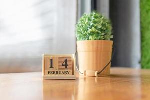 Wooden calendar show of February 14 on table with flower in vase, Valentine's day concept photo