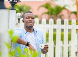 alegre hombre afroamericano sosteniendo vidrio de papel sonriendo al aire libre y mirando a la cámara foto