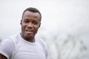 alegre hombre afroamericano con auricular inalámbrico sonriendo al aire libre y mirando a la cámara foto