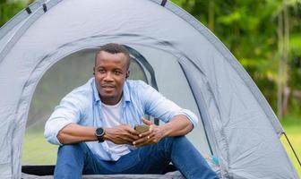 Cheerful african american man enjoying with smartphone in the park photo