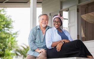 Senior asian man and cheerful african american woman sitting relax and looking at camera photo