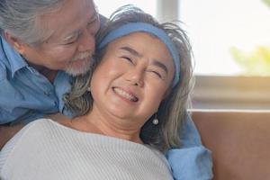 Close up portrait of happy senior asian couple hugging in living room photo