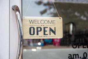 Open sign wooden broad through the glass of window at coffee shop photo