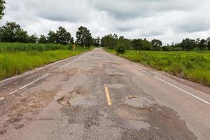 Damaged asphalt pavement road with potholes photo