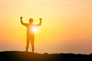 silueta de hombre con camino de recorte celebración éxito felicidad en la cima de una montaña en la playa cielo de la tarde fondo de puesta de sol, deporte y concepto de vida activa foto