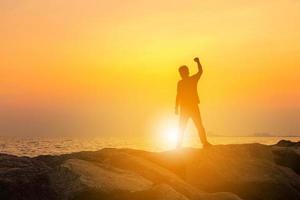 silueta de hombre con camino de recorte celebración éxito felicidad en un fondo de atardecer de cielo de piedra, deporte y concepto de vida activa. foto