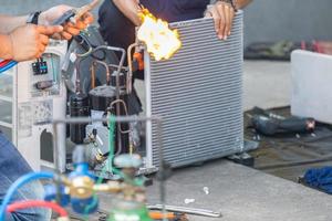 Close up of Air Conditioning Repair team use fuel gases and oxygen to weld or cut metals, Oxy-fuel welding and oxy-fuel cutting processes, repairman on the floor fixing air conditioning system photo