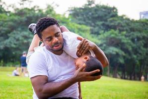 alegre padre afroamericano e hijo jugando en el parque, conceptos familiares de felicidad, padres e hijos juegan en el parque foto