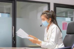 Young woman telephone operator with headset wear protection face mask against coronavirus, Customer service executive team working at office