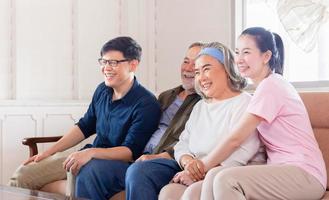 Cheerful Asian family watching television in living room, Senior father mother and middle aged son and daughter sitting on sofa, Happiness family concepts photo