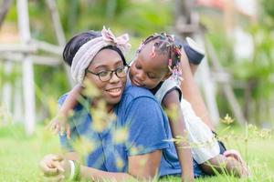 African american girl playing on the back of her mother, Happy mother and daughter laughing together outdoor photo