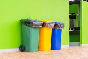 Group of colorful recycle bins green background, Different colored bins for collection of recycled materials. Garbage bins with garbage bags. Environment and waste management concept. photo